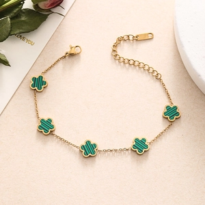 Detailed macro shot of gold double layer chain bracelet with green five-petal flower charms