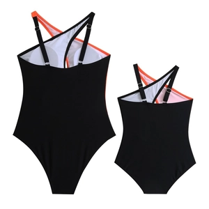 Flat lay of black and orange matching mother and daughter swimwear with cross straps