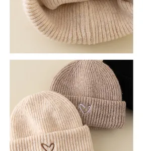 Detailed knit texture of rib-knit beanies with heart embroidery in three soft colors