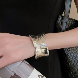 Detail of silver wide cuff bracelet with hammered texture and polished mirror finish
