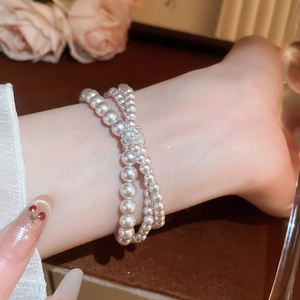 Detail of elegant double-layer pearl bracelet with rhinestone center on model's wrist