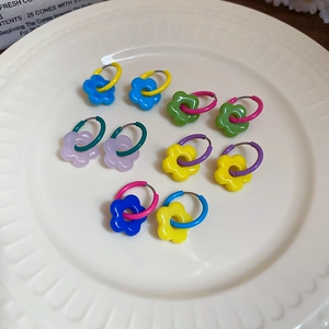 Detailed close-up of colorful floral hoop earrings with resin petals in a white ceramic dish