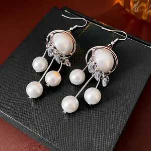 Elegant planet pearl tassel drop earrings with zircon crystals on a black jewelry box