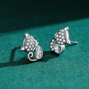 Sparkling S925 sterling silver cat stud earrings with white cubic zirconia on green background