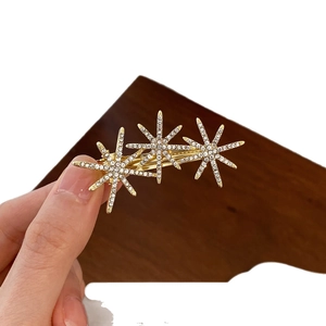 Elegant gold French side hair clip featuring rhinestone encrusted star flowers held in hand
