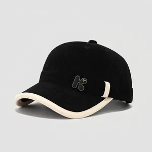 Close-up of black corduroy toddler baseball cap featuring a metal K letter badge