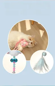 Detail of cat wand featuring pink flower, metal double bells, and light blue feathers