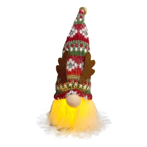 Close-up of glowing Christmas gnome plush with reindeer antlers and a golden bell