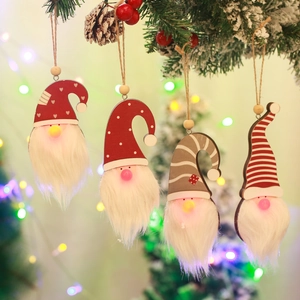 Close-up of four LED glowing forest gnomes hanging on snowy Christmas tree branches