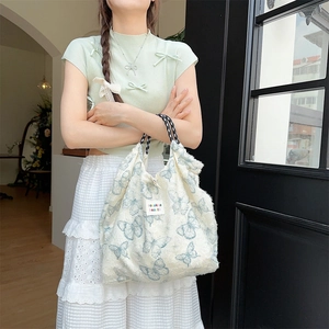 Detailed shot of white canvas tote bag with blue butterfly print and woven handles