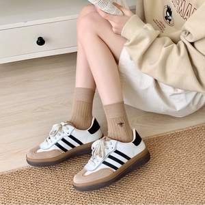 Detail of bee embroidery on khaki cotton crew socks worn with stylish sneakers