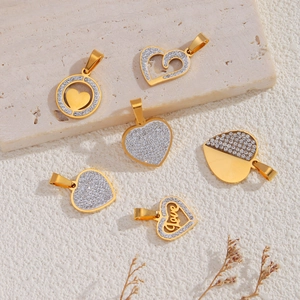 Detailed view of 18k gold plated stainless steel heart charms with zircons on stone tray