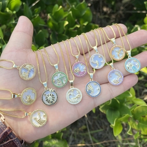 Detailed shot of 18K gold zodiac pendants featuring mother of pearl and colorful zircons
