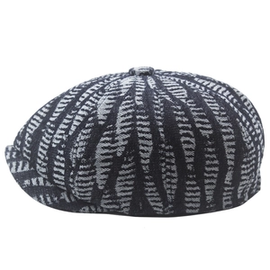 Close-up of black and white newsboy cap featuring tweed texture and top button detail