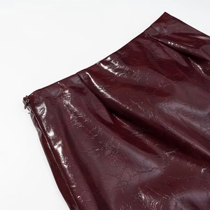 Dettaglio ravvicinato della gonna in pelle PU rosso scuro lucida con zip laterale a scomparsa
