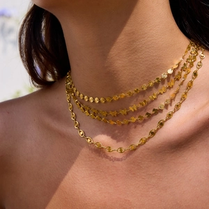 Dettaglio della collana dorata a tre strati con farfalla e maglie a catena strutturate