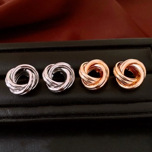 Détail de boucles d'oreilles nœuds entrelacés en argent et or rose sur support noir