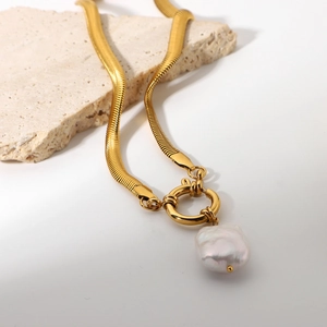Close-up of 18K gold snake chain necklace featuring a white baroque pearl on stone