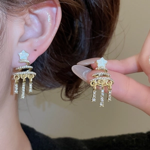Detail showing elegant gold star earrings with rhinestone tassels worn by a model