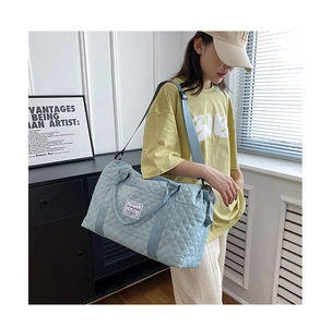 Detailed view of light blue quilted travel bag with adjustable strap worn by a model