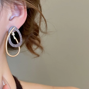 Détail de boucles d'oreilles géométriques avec anneau en métal doré et pendentif bois