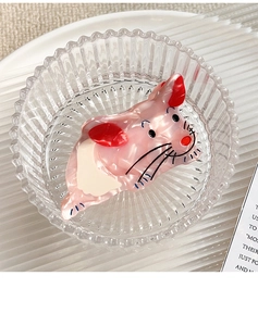 Detailed top view of pink mouse-shaped acetate hair claw clip in a glass bowl