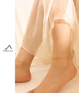 Close-up of gold and silver stainless steel anklets worn on model ankles