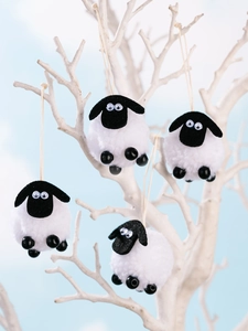 Lot de quatre décorations en peluche de mouton noir et blanc suspendues à une branche
