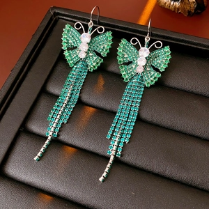 Dettaglio di orecchini vintage a farfalla con nappe e zirconi verdi in esposizione