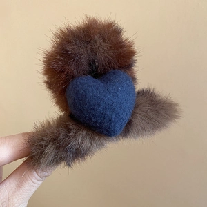 Vue détaillée d'une pince à cheveux en peluche marron ornée d'un cœur en feutre bleu