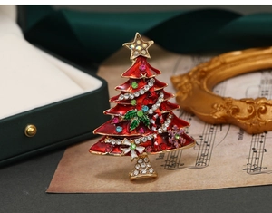Close-up of a festive Christmas tree brooch with red enamel and colorful rhinestones