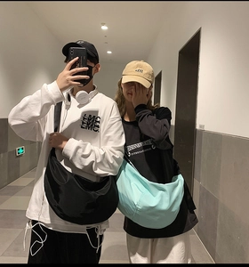 Detail of nylon crossbody bags in black and light blue shown on a model in a mirror selfie