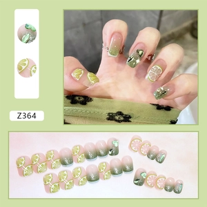 Detail of green gradient press-on nails featuring lemon slices and heart-shaped 3D charms