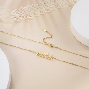 Detail view of a gold mountain range hollow necklace with fine link chain and lobster clasp