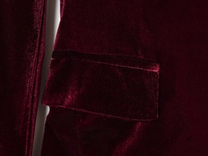 Macro shot of burgundy velvet fabric texture and stitching detail on the pocket flap