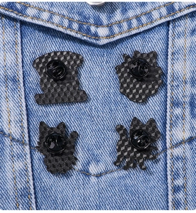 Close-up of four black skull cat pins with rubber backings pinned on denim jacket pocket