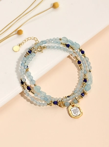 Detail of beaded multilayer bracelet with blue crystals and a gold face pendant charm