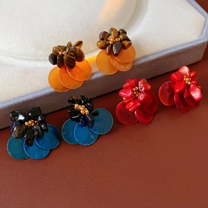 Detailed view of vintage shell and tiger eye earrings in orange, blue, and red floral designs