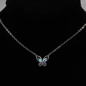Detail of butterfly pendant with iridescent wings and purple gem on silver chain