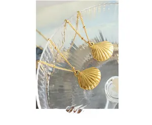 Macro shot of gold-plated scallop shell pendants with small beads on a fine gold chain