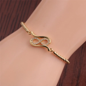 Detail of gold infinity bracelet with sparkling zircons on a model's wrist