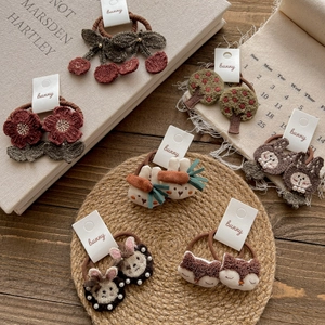 Set of 6 cute animal and fruit knit elastic hair ties for girls on a rustic wooden background