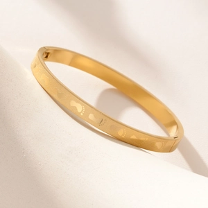 Polished gold stainless steel bangle featuring delicate footprints pattern engraving