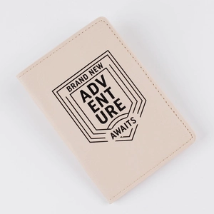 Detailed view of beige PU leather passport holder with Adventure Awaits printed text