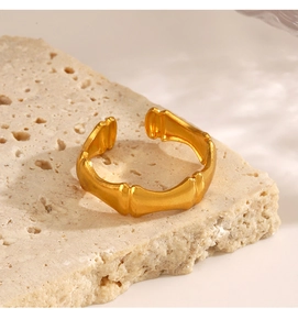 Detailed close-up of golden bamboo-joint style open ring on textured stone surface