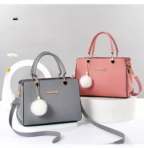 Detail view of pink and grey PU leather handbags with fuzzy pompom charms on stands