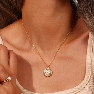 Détail du collier pendentif cœur doré avec strass et bague chaîne en perles assortie