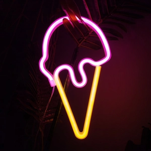 Pink and yellow LED neon sign in ice cream cone shape glowing on dark leaf background
