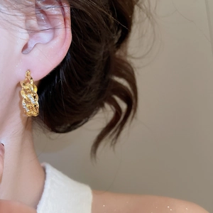 Close-up of vintage gold chain hoop earrings with sparkling diamonds on female model