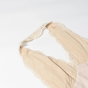 Détail d'une robe beige avec col en V, bordure en dentelle et motif à carreaux fins